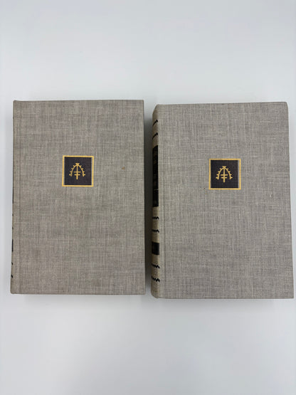 Two gray cloth bound books with gold embossed vignettes on a white background.