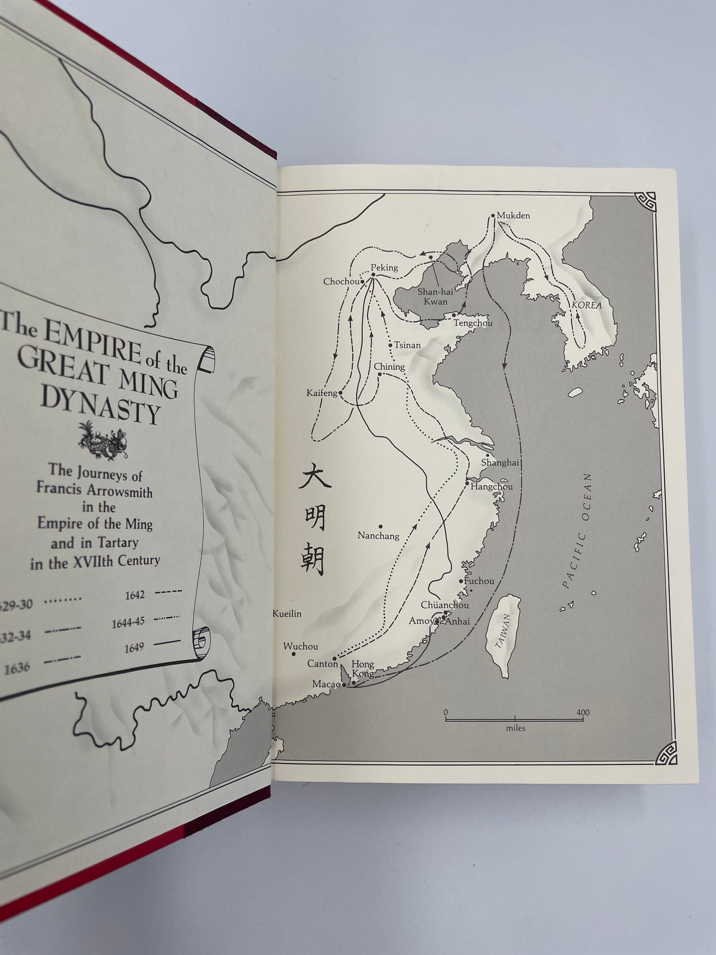 Open book showing a map of the Empire of the Great Ming Dynasty on a light gray background