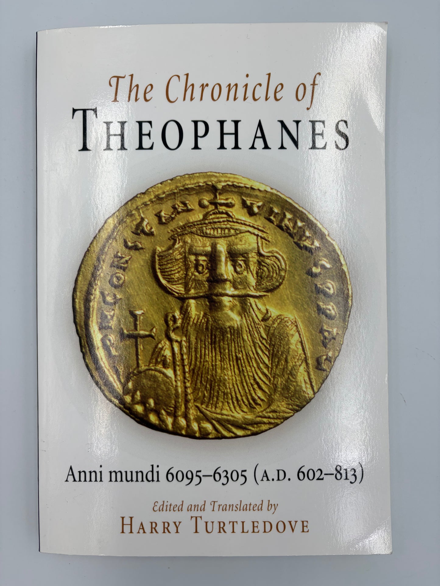 Book cover of 'The Chronicle of Theophanes' with a gold coin featuring a king's portrait on a gray background.
