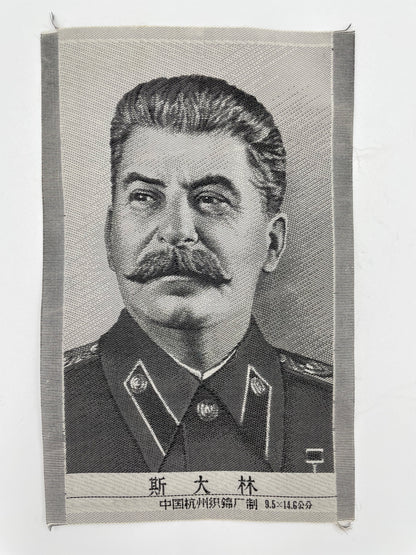 A silk portrait of Stalin, featuring a black and white image of the leader with a stern expression, likely from the 1950s.