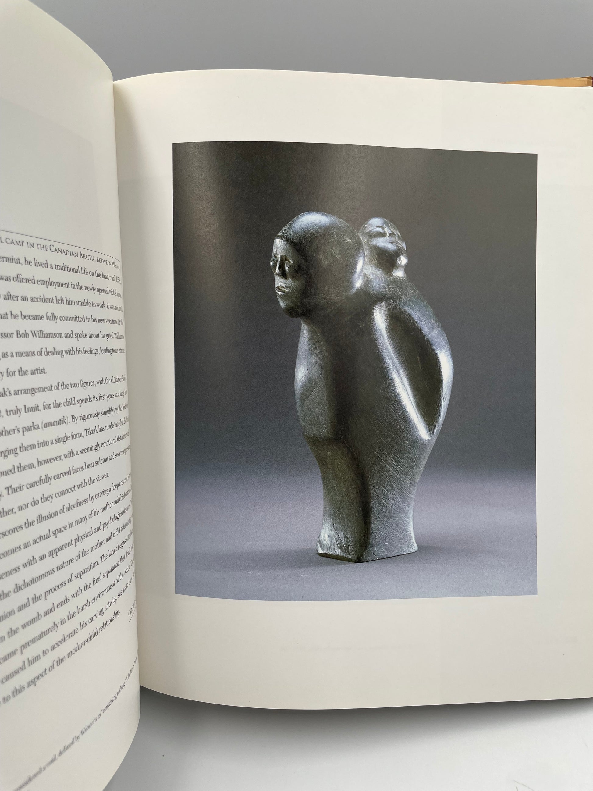 Open book with a photograph of a sculpture on a gray background