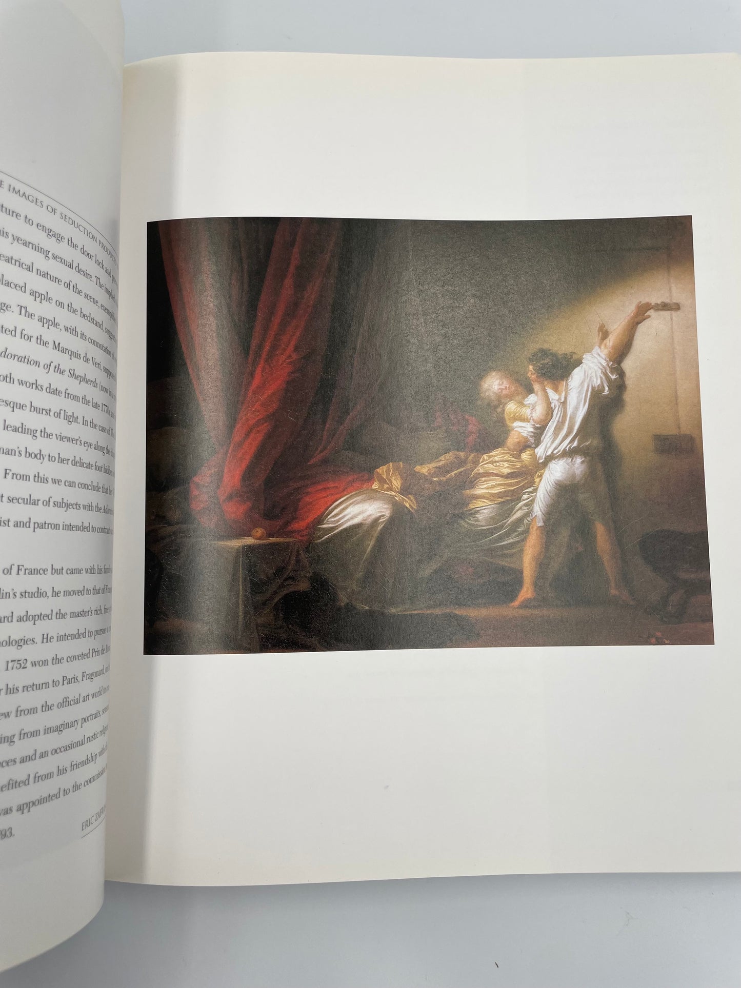 Open book with a classical painting of a woman and a man in a room.