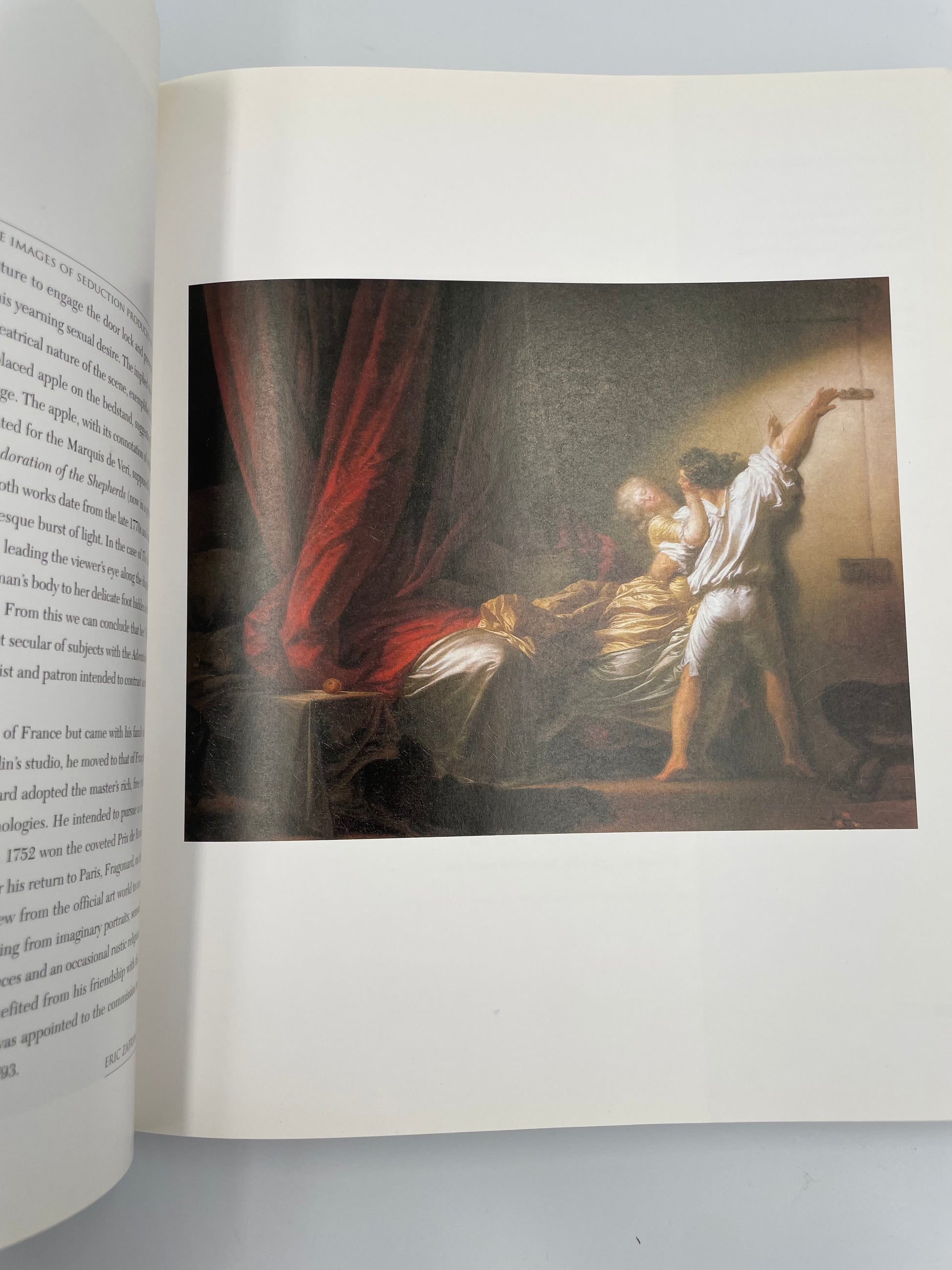 Open book with a classical painting of a woman and a man in a room.