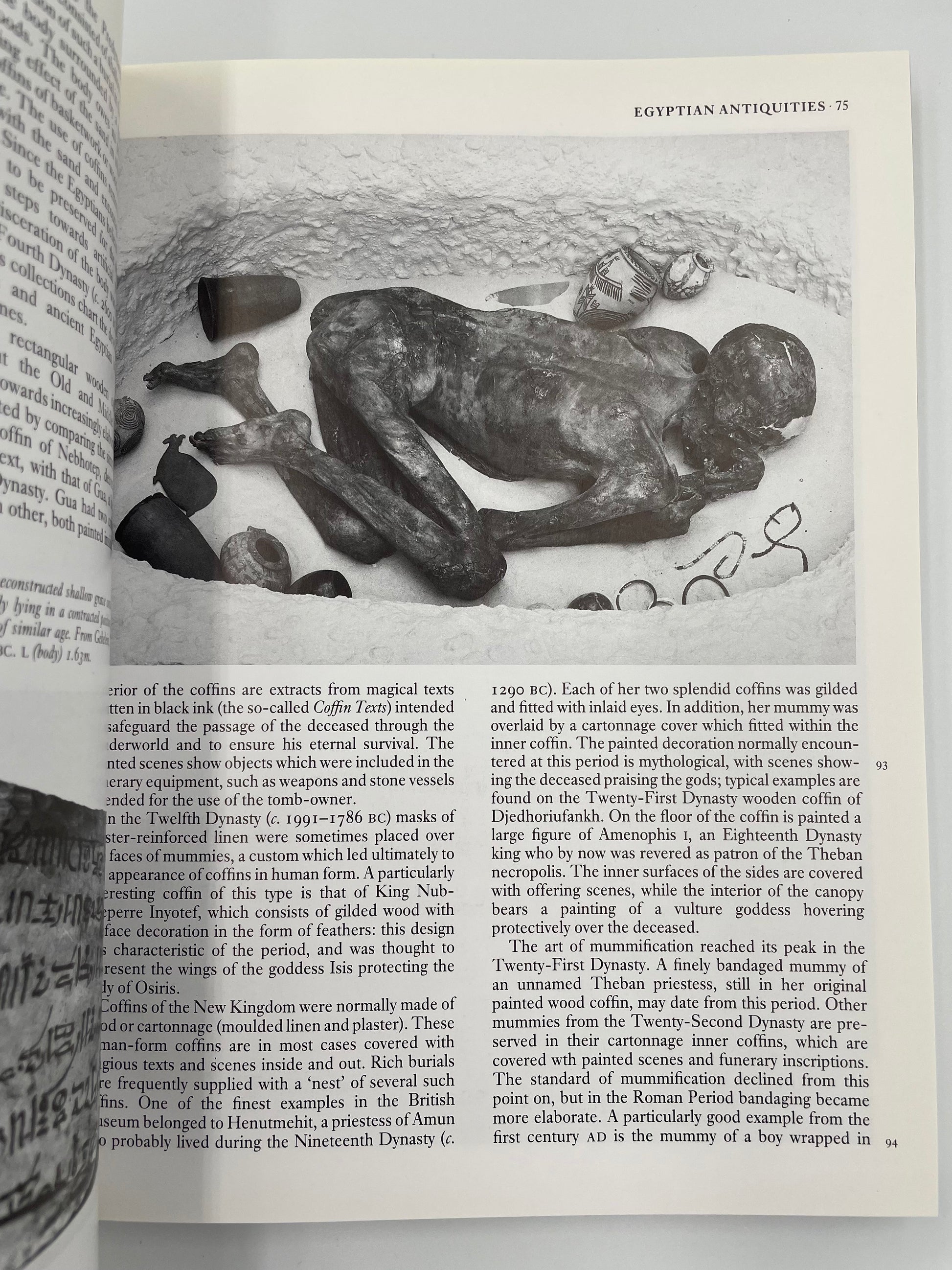 Open book showing an illustration of a mummy and text on Egyptian antiques.