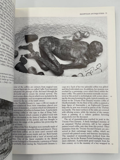 Open book showing an illustration of a mummy and text on Egyptian antiques.