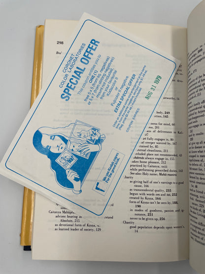 Open book with an original blue and white photo development store coupon from August 1979 inserted to a page from the book, ‘Bhagavad-Gita As It Is’.