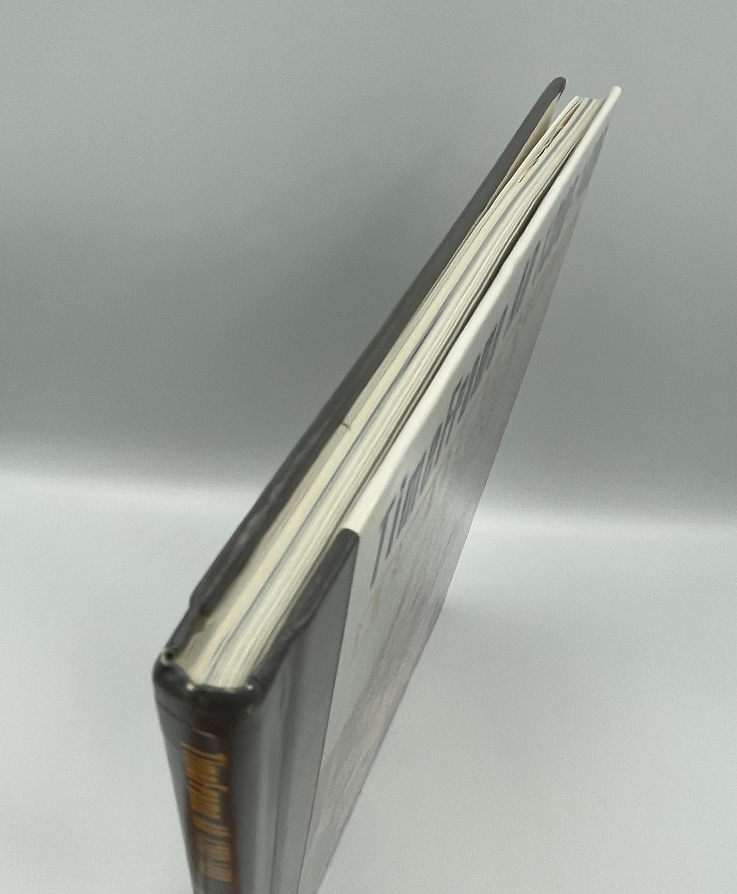 Close-up of a book top edges with a metallic cover on a light gray background
