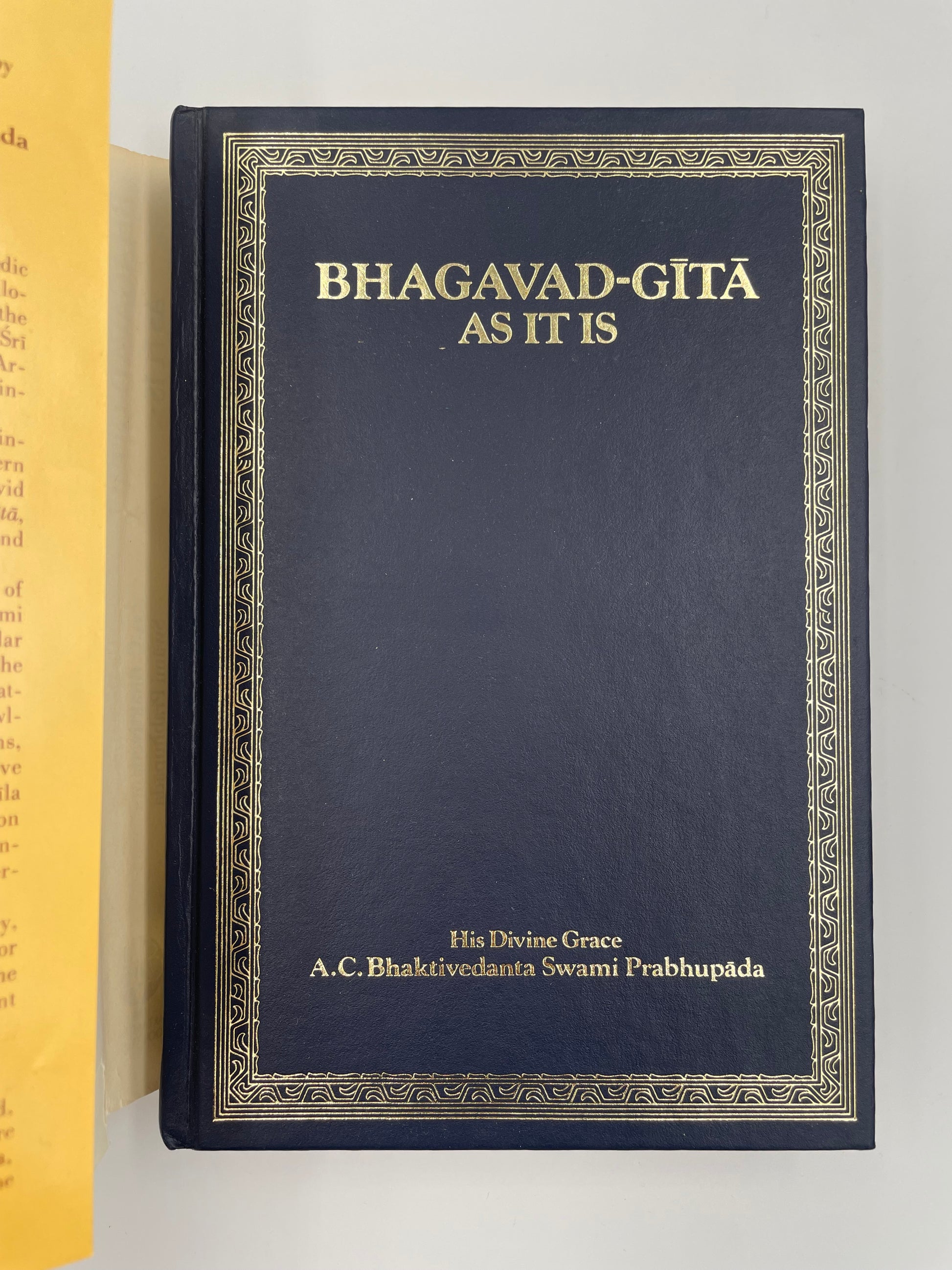 Dark blue book titled 'Bhagavad Gita As It Is' with gold text on a white background