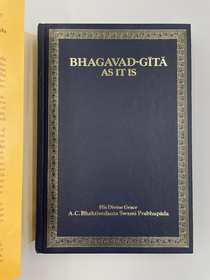 Dark blue book titled 'Bhagavad Gita As It Is' with gold text on a white background