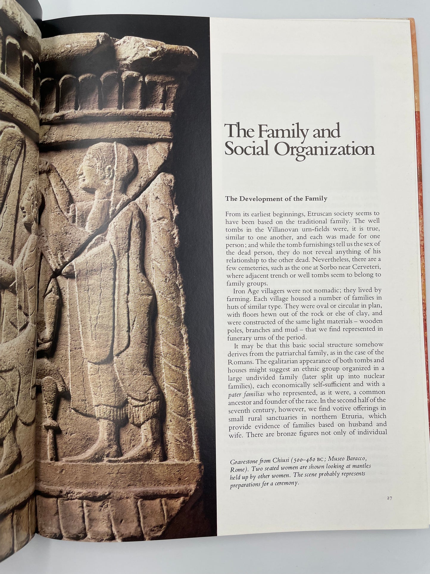 Book open to a page about family and social organization with an ancient stone carving on a white background from the book, 'The Etruscans' by Mauro Cristofani.